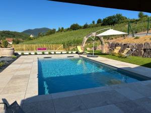 a swimming pool in a yard with chairs and an umbrella at Gite Ungersberg in Itterswiller