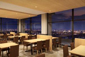 a restaurant with tables and chairs and a view of the city at Ooedo Onsen Monogatari Premium Minoh Kanko Hotel in Minoo