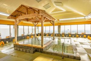 a large pool in a building with yellow chairs at Ooedo Onsen Monogatari Premium Minoh Kanko Hotel in Minoo
