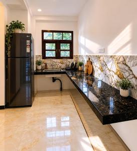 a kitchen with a black counter top and a refrigerator at Suriya villa in Poddala