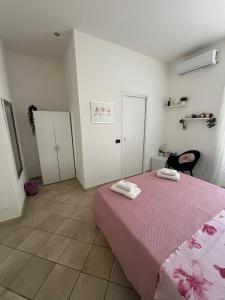 a bedroom with a pink bed with two towels on it at Il Corallo in Terracina