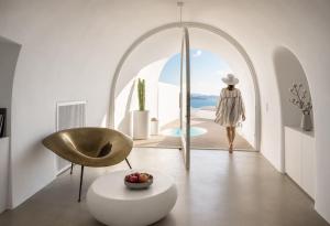 a woman walking into a white room with a mirror at Saint Santorini in Oia +183 photos