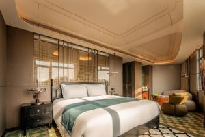 a bedroom with a large bed and a chair at Xiamen Lujiang Harbourview Hotel-panoramic sea views over Gulangyu in Xiamen