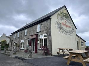 a building with two picnic tables in front of it at The Hedgerow Kilshanny in Kilshanny