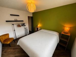 a bedroom with a white bed and a green wall at A Chatenois le Repère d'Anna in Châtenois