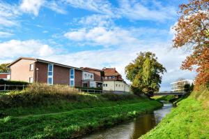 a river with houses and a bridge in the background at Hotel Bonke in Nordhorn