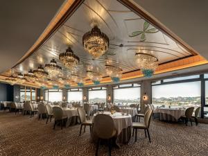 a dining room with tables and chairs and chandeliers at Xiamen Lujiang Harbourview Hotel-panoramic sea views over Gulangyu in Xiamen