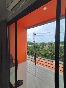 an open door to a balcony with orange walls at Sleek Modern Studio in Rawai, Phuket in Ban Saiyuan (1)