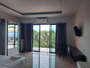 a bedroom with a bed and a desk and a balcony at Sleek Modern Studio in Rawai, Phuket in Ban Saiyuan (1)