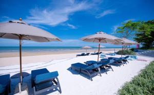 a beach with chairs and umbrellas and the ocean at BLU Diamond Cha Am in Ban Bo Khaem