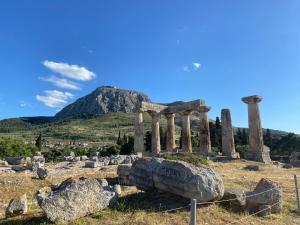 an ancient temple with a mountain in the background at Corinth Beach Apartment and Hostel in Korinthos