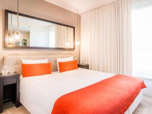 a bedroom with a large bed with orange pillows at Aparthotel Adagio Marseille Timone in Marseille