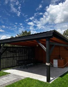 a pavilion with a black roof on a patio at 10 osobowy Bania House Okuninka rowerek wodny jacuzzi sauna 1200 m do centrum Okuninki 6 km do Włodawy in Włodawa