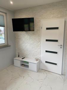 a white door with a tv on a brick wall at Biebrzańska Przystań 7 in Goniadz +5 photos
