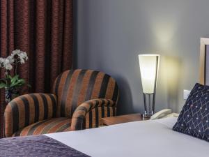 a bedroom with a bed and a chair and a lamp at Mercure Albury in Albury