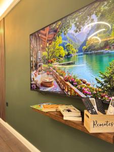 a television hanging on a wall with a picture of a lake at Top Centre Apartment 5 mins to beach in Burgas