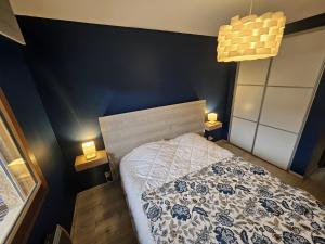 a bedroom with a bed with a blue wall at Le Haut du Rosay in Sallanches