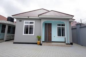 a small white house with a blue door at Akibo Residency Apartment in Mwanza