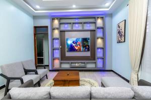 a living room with a couch and a tv at Akibo Residency Apartment in Mwanza