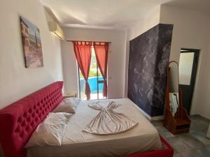 シェンジンにあるAdriatic Residence Shengjinの赤いヘッドボードと窓のあるベッドのある寝室