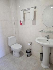 a white bathroom with a toilet and a sink at Harmony Inn in Almaty +14 photos