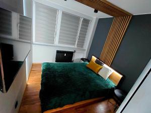 a bedroom with a green bed and a window at Apartament IRESTAN - Komfortowy wypoczynek w sercu Karkonoszy in Jelenia Góra