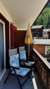 two chairs and an umbrella on a balcony at Hotel Rhodania in Zermatt