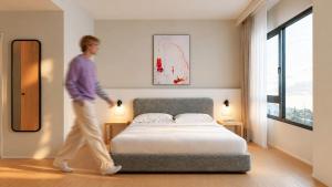 a man walking past a bed in a bedroom at Stey Stavanger in Stavanger