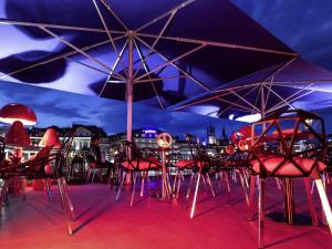 eine Gruppe von Stühlen und Sonnenschirmen auf einem Dach in der Unterkunft ibis Styles Lausanne Center MadHouse in Lausanne
