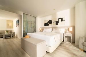 a white bedroom with a large bed and a chair at Hotel Helios Costa Tropical in Almuñécar +50 photos