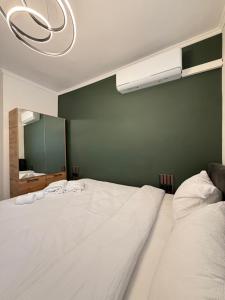 a bedroom with a large white bed with a green wall at Top Centre Apartment 5 mins to beach in Burgas