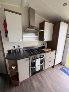 a small kitchen with a stove and white cabinets at Skyline in Lossiemouth