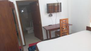 a bedroom with a bed and a desk and a toilet at Bhaavi Guest Inn in Jaffna