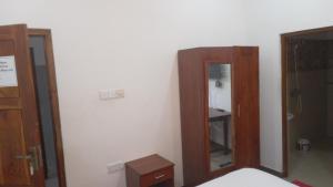 a bedroom with a mirror and a wooden cabinet at Bhaavi Guest Inn in Jaffna