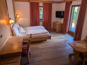 a bedroom with a bed and a desk and a tv at Sport Hotel Wildgall in Anterselva di Mezzo