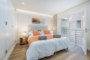a white bedroom with a large bed with orange pillows at Apartment Vistamar III in Port de Pollensa +7 photos