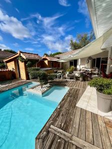 a backyard with a swimming pool and a wooden deck at La maisonnette de chez Pascalou in Lège-Cap-Ferret