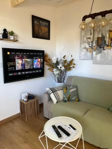 a living room with a couch and a tv on the wall at La maisonnette de chez Pascalou in Lège-Cap-Ferret