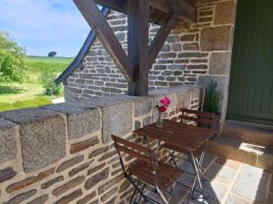 a patio with two chairs and a table with flowers at La Valaisienne in Val Couesnon +14 photos