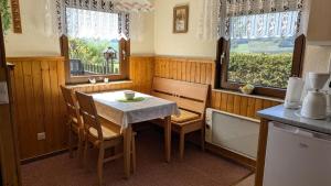 a kitchen with a table and chairs and two windows at Ferienhaus am Wald in Augsburg