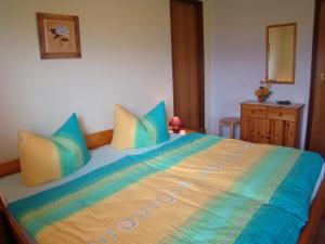 a bedroom with a large bed with blue and yellow pillows at Ferienhaus am Wald in Augsburg