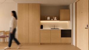 a woman walking through a kitchen with a sink at Stey Stavanger in Stavanger