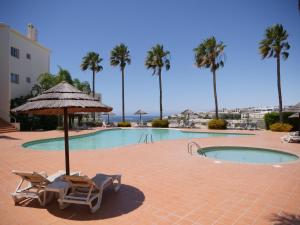 two chairs and an umbrella next to a swimming pool at Large three-bedroom apartment in Lagos