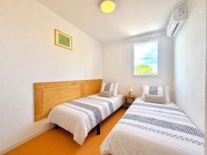 two beds in a small room with a window at La cachette du Mas, 4 pers Piscine à Calvisson in Calvisson