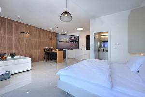 a bedroom with a white bed and a flat screen tv at קולינה וארדה in ‘Amqa