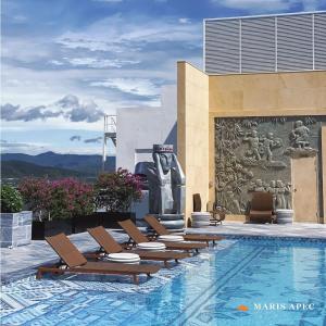 a pool with lounge chairs and a statue on the side of a building at Maris Apec Tuy Hoà in Tuy Hoa