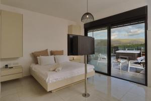 a bedroom with a bed with a tv and a balcony at קולינה וארדה in ‘Amqa +91 photos