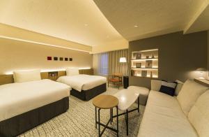 a hotel room with two beds and a couch at Richmond Hotel Aomori in Aomori +60 photos