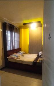 a bed in a room with a yellow wall at Gerry's Place in Iloilo City