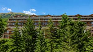 a large building with trees in front of it at Hostdomus - Sansicario R20 in San Sicario